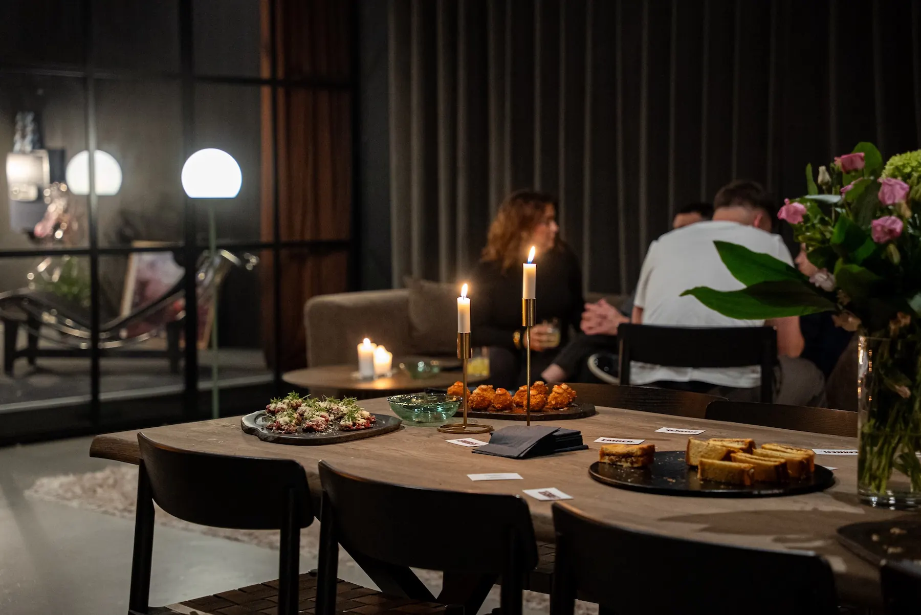 Gæster omkring bordet med snacks og levende lys hos EMBER